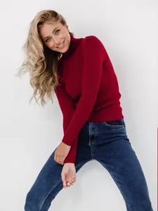 Detailansicht eines dunkelroten Rollkragen-Strickpullovers für Damen mit blauer Jeans.