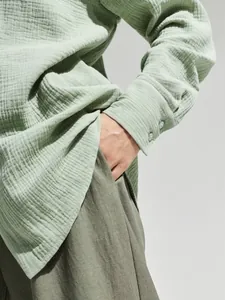 Primo piano di camicia in garza di cotone verde menta che mostra la trama traspirante crinkle