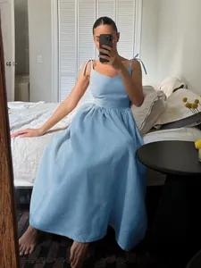 Light blue V-neck midi dress with adjustable tie-up shoulder straps in lifestyle setting
