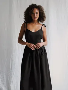 Elegant black pure cotton V-neck midi dress featuring adjustable tie-shoulder straps.