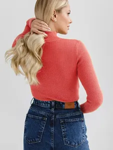 Back view of a slim fit coral ribbed turtleneck knit sweater worn by a model in studio