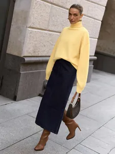 Elegantes Model trägt einen blassgelben Oversize-Rollkragenpullover und einen Jeansrock