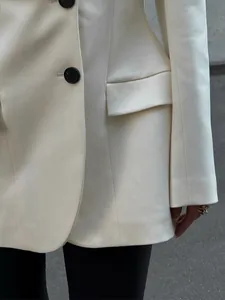 Dettaglio di un blazer slim fit panna con bottone, tasca e trama del tessuto fine