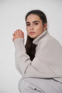 Detailansicht eines Modells in einem eleganten beigen Oversized-Strickrollkragenpullover.
