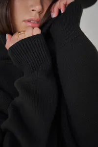 Nahaufnahme der hochwertigen, weichen, schwarzen Strickstruktur eines Rollkragenpullovers