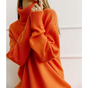 Detail eines leuchtend orangen Oversize-Rollkragenpullovers mit Strickstruktur