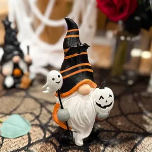 Close-up detail view of a Halloween gnome resin ornament holding ghost and pumpkin masks