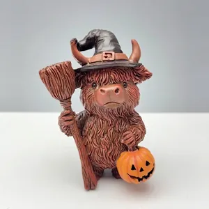 Detalle de figura de vaca Highland con sombrero de bruja y calabaza Halloween