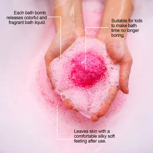 Primer plano de una bomba de baño rosa efervescente en las manos con espuma perfumada