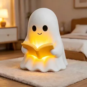 Close-up of cute ghost night light reading a book with warm glowing illumination