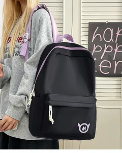 Detail shot of a black and purple student backpack worn by a model in a casual setting