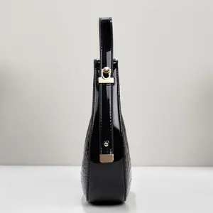 Detailansicht einer stilvollen schwarzen Lackleder-Mondtasche mit goldenen Akzenten.
