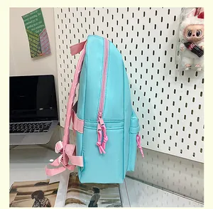 Side view detail of a light blue and pink school backpack in a study desk setting