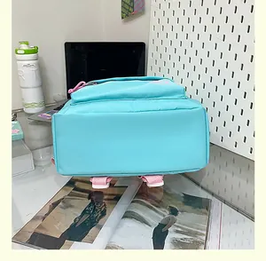 Detailed bottom view of a minimalist turquoise school backpack featuring pink straps