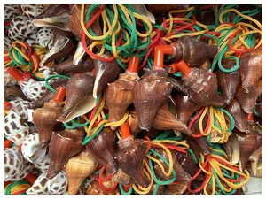 Detail von handgefertigten Muschelpfeifen mit bunten Schnüren und roten Mundstücken