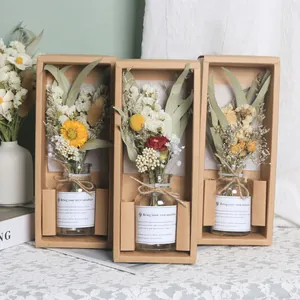 Detailansicht von drei getrockneten Blumen in Glasflaschen in Kraftpapier-Geschenkkartons