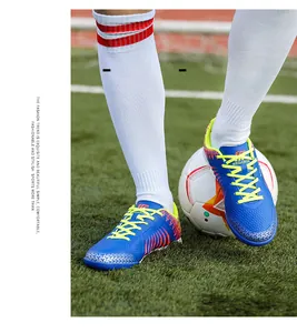 Detail view of blue and yellow men's soccer cleats on a grass field with a soccer ball.