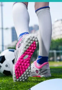 Detailed view of the pink turf sole on children's fleece-lined winter soccer shoes in a stadium