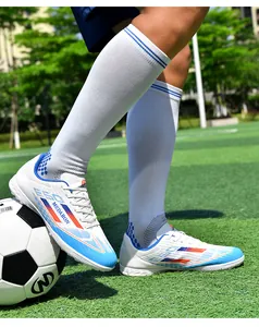 Action close-up of vibrant blue and white soccer cleats with turf studs on green field