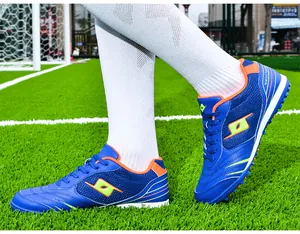 Close-up of blue and orange professional TF soccer shoes for men and kids on turf