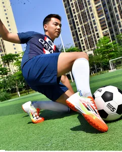 Close-up of colorful soccer shoes with long studs on a green turf field.