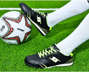 Black and neon green TF soccer shoes shown in action on a professional turf field.