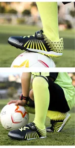 Close-up of kids professional turf soccer shoes on a field with a soccer ball