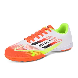 Vibrant white soccer cleats with orange and lime green accents for turf training.