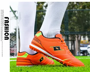 Detailed close-up view of professional orange TF soccer cleats on green grass
