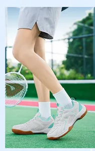Vue latérale de chaussures de badminton blanches respirantes sur un terrain vert