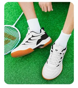Vue de dessus de chaussures de badminton blanches pour hommes avec semelles en gomme sur gazon.