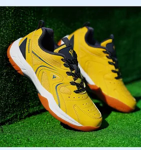 Vue latérale de chaussures de badminton jaunes avec semelles en gomme antidérapantes sur herbe