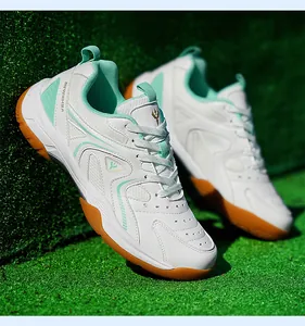 Détail de chaussures de badminton respirantes blanches et vert menthe sur gazon artificiel