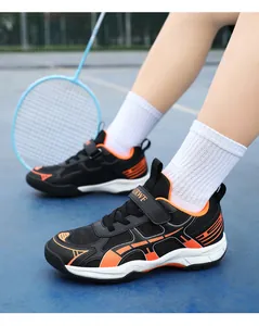 Close-up van zwarte en oranje badmintonschoenen voor kinderen op een sportterrein