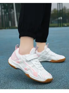 Lichte roze en witte badminton schoenen voor meisjes op een buiten sportveld court