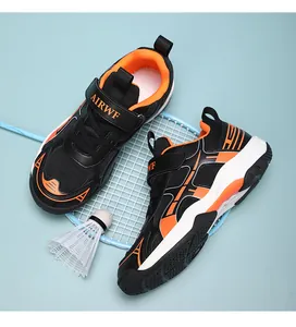 Close-up van lichtgewicht badminton-kinderschoenen in zwart en oranje met badmintonracket