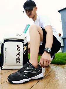 Close-up of black badminton sneaker on a model's foot in an outdoor setting