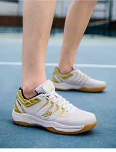 Gedetailleerd beeld van ademende witte badmintonschoenen met gouden accenten op veld.