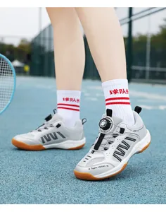 Breathable kids' badminton shoes with rotary buckle closure on a sports court