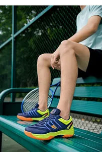 Dichtbij van ademende marineblauwe en neongele badmintonschoenen op een sportbankje