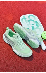 Professional breathable mint green pickleball athletic shoes displayed on a red sports court