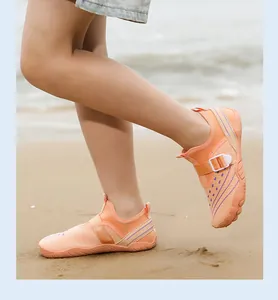 Close-up detail of children's breathable orange water shoes worn on a sunny sandy beach