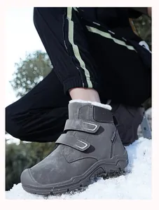 Detail view of gray children's snow boots with warm plush lining on snow background