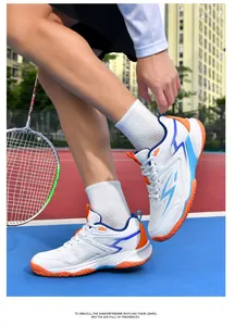 Gros plan de chaussures de volley-ball blanches avec accents bleus et orange sur terrain.