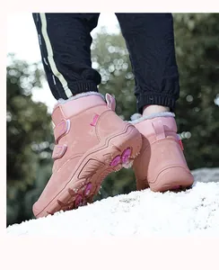 Detail of pink children's high-top snow boots with warm fleece lining on snow.