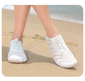 Makroansicht weißer Zehenschuhe mit rosa Wellenmuster am Sandstrand für Wassersport