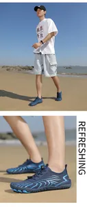Nahaufnahme eines Mannes mit rutschfesten blauen Badeschuhen an einem sonnigen Sandstrand