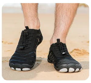 Nahaufnahme von schwarzen Fünf-Finger-Wasserschuhen auf einem Sandstrand zum Wandern und Tauchen