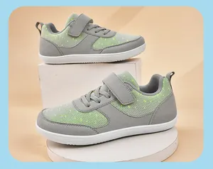 Detail shot of grey and neon green wide-toe kids sneakers on white display stands.