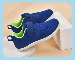 Side view of breathable blue mesh kids' sneakers with neon green lining on white pedestals